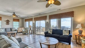 En rummelig stue med en stor sofa, et sofabord og en balkon med havudsigt.