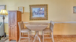 Un comedor con una mesa y sillas de madera, un aparador de madera y un cuadro en la pared.