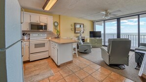 Cocina compacta con microondas, horno y comedor con televisión y asientos.