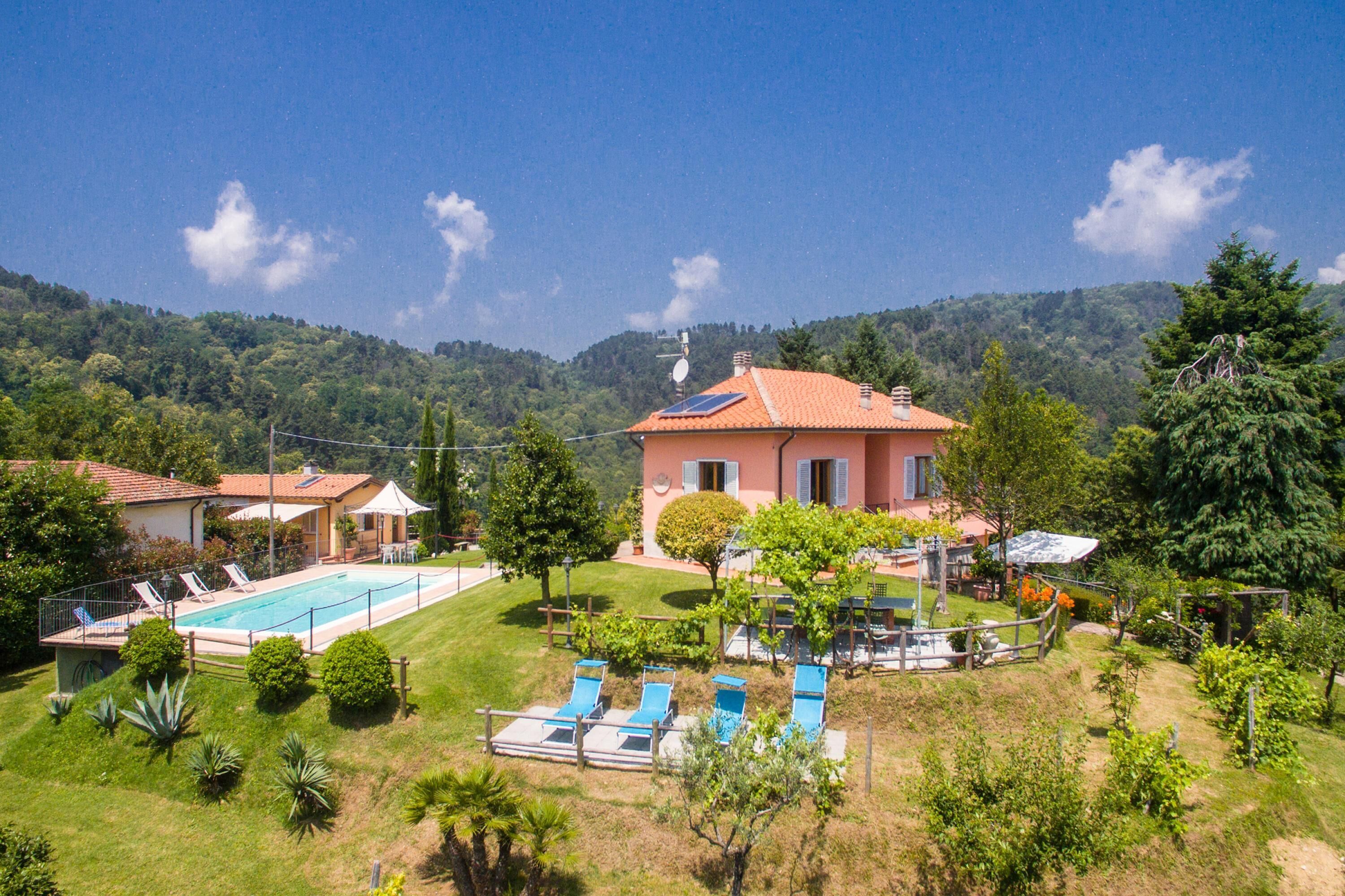 A house with a swimming pool, sun loungers, and a garden.