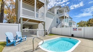 A two-story house with a swimming pool, a covered patio, and a fenced backyard.