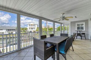 A covered outdoor patio with a table and chairs, a ceiling fan, and a view of a residential area. - Rucker Cottage - Crabbing & fishing off floating dock, private pool (Garden City Beach)