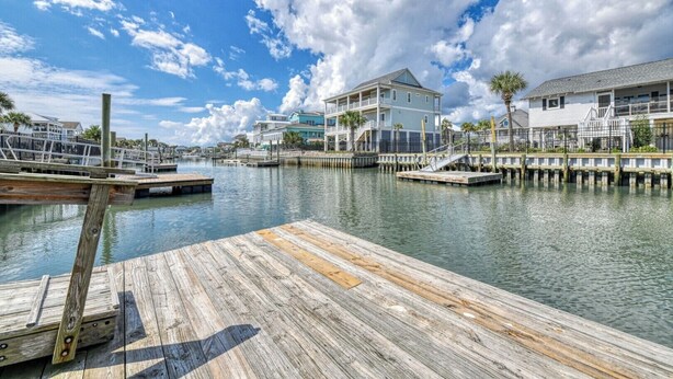 A waterfront property with a dock, a large house with a balcony, and a smaller building. - Rucker Cottage - Crabbing & fishing off floating dock, private pool (Garden City Beach)