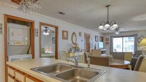 A kitchen with a double sink, wooden cabinets, a dining area with a table and chairs, and a ceiling fan.