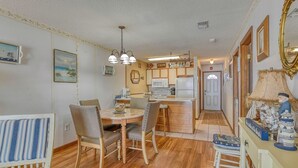 A cozy kitchen with wooden cabinets, a dining area with striped chairs, and a small bar area with stools.