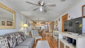 A living room with a sofa, chairs, a coffee table, a TV, and a ceiling fan.