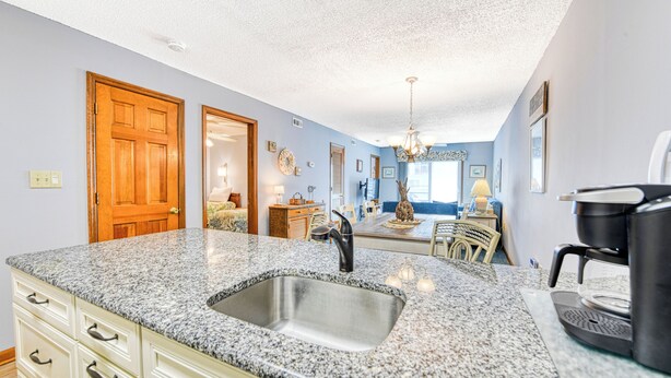 A kitchen with granite countertops, a stainless steel sink, and a coffee maker. - Sandy Shores II 209 - Two-bedroom, two-bath oceanview condo in GCB (Garden City Beach)