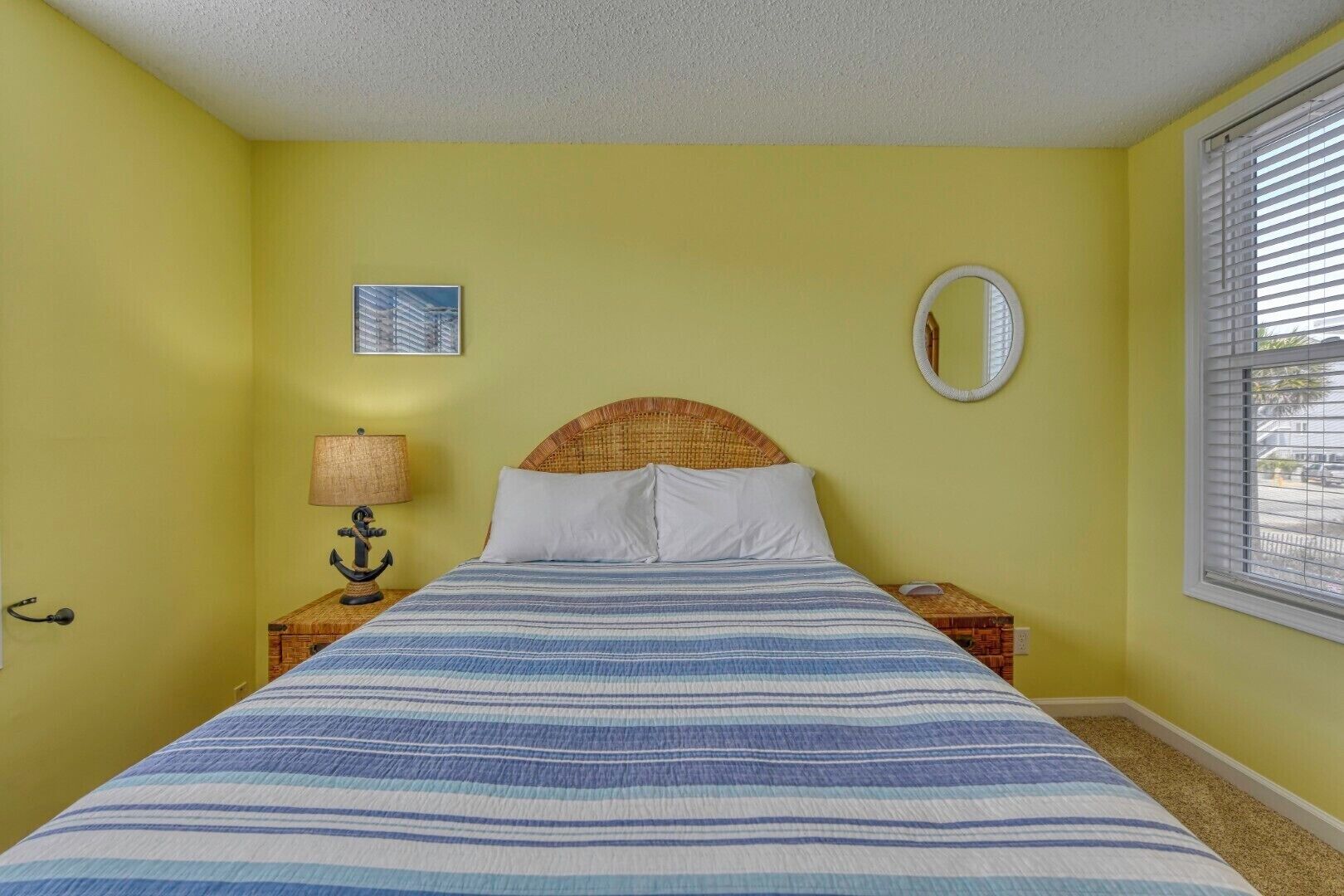 Une chambre à coucher avec un lit, une table de chevet, une lampe, un miroir et une fenêtre.