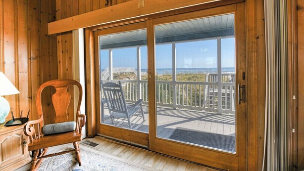 Un intérieur en bois avec une porte-fenêtre coulissante donnant sur une terrasse extérieure.