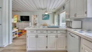 A kitchen with white cabinetry, a tiled backsplash, and a microwave. - Charming Coastal - 5 Bedroom, 4 Bath Beach House with Private Pool (Garden City Beach)