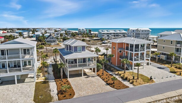 A coastal residential area with multi-story houses, a paved walkway, and a beach in the background.