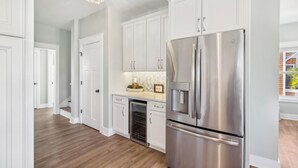 A modern kitchen with white cabinetry, stainless steel appliances, and a built-in oven.