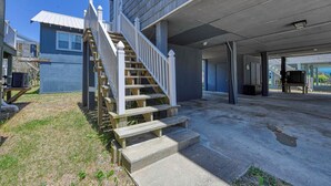 A residential building with a covered garage, a wooden staircase, and a concrete driveway. - Summer House - Clinkscales - Three-bedroom, two-bath beach house with Wi-Fi (Garden City Beach)