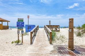 A wooden boardwalk leading to a beach with signs for Anglers Ave, beach ordinance, and public works.