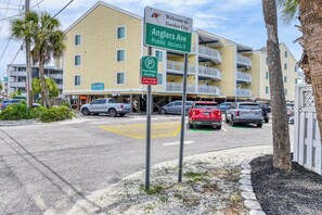 A multi-story building with balconies, a sign indicating public access to Anglers Ave, and a parking sign with a no parking time restriction.