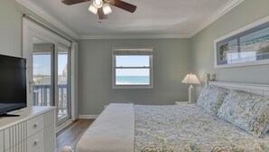 Une chambre à coucher comprenant un lit, une télévision, un ventilateur de plafond, une fenêtre avec vue et une commode.