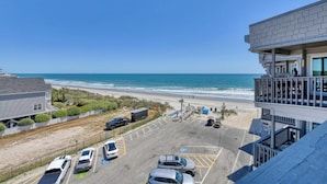 Un hôtel situé en bord de mer, doté d’un parking, offrant une vue sur la plage et comprenant un bâtiment avec un balcon donnant sur l’océan.