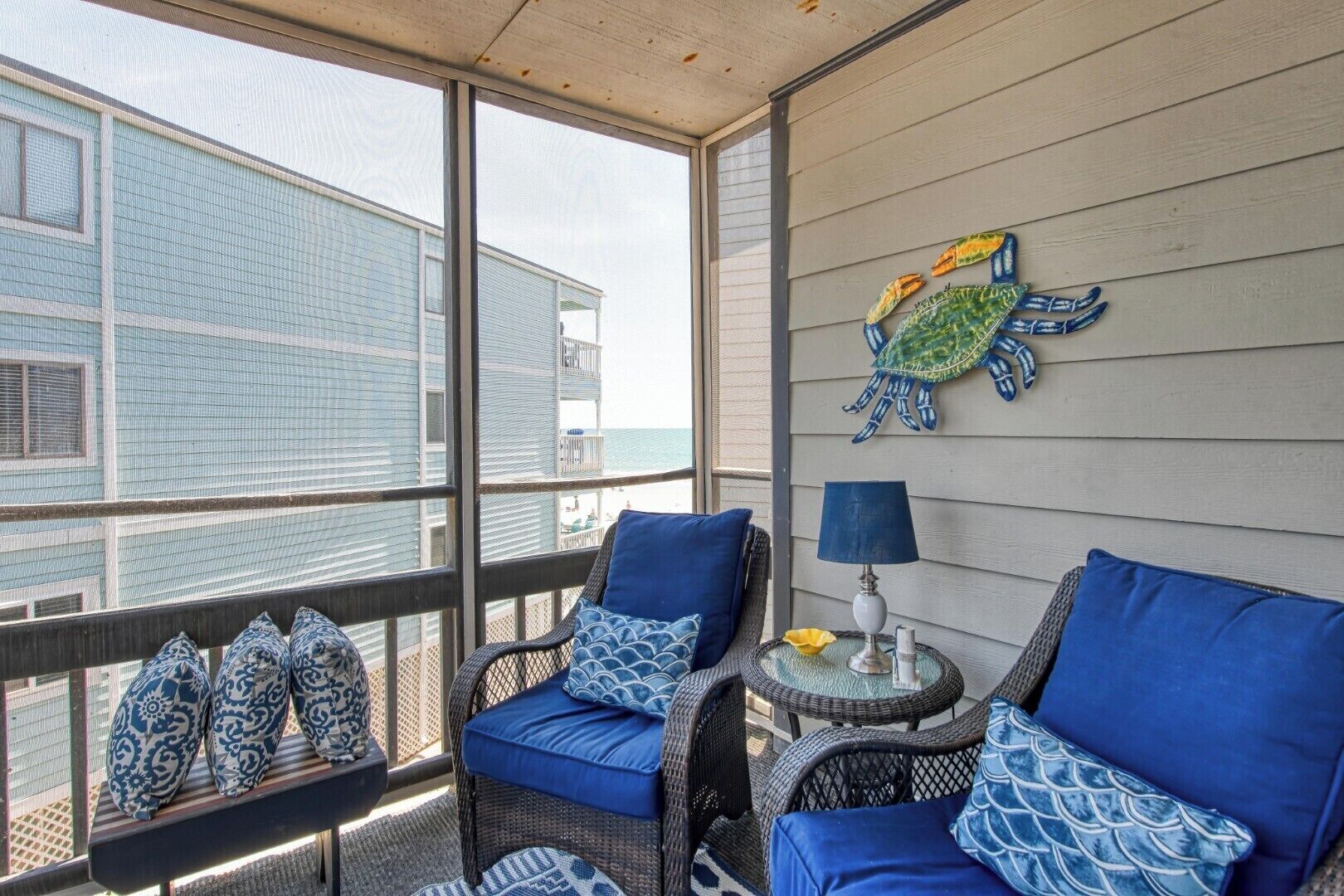 A balcony with wicker furniture, a lamp, and a decorative turtle wall art.