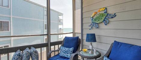 A balcony with wicker furniture, a lamp, and a decorative turtle wall art.