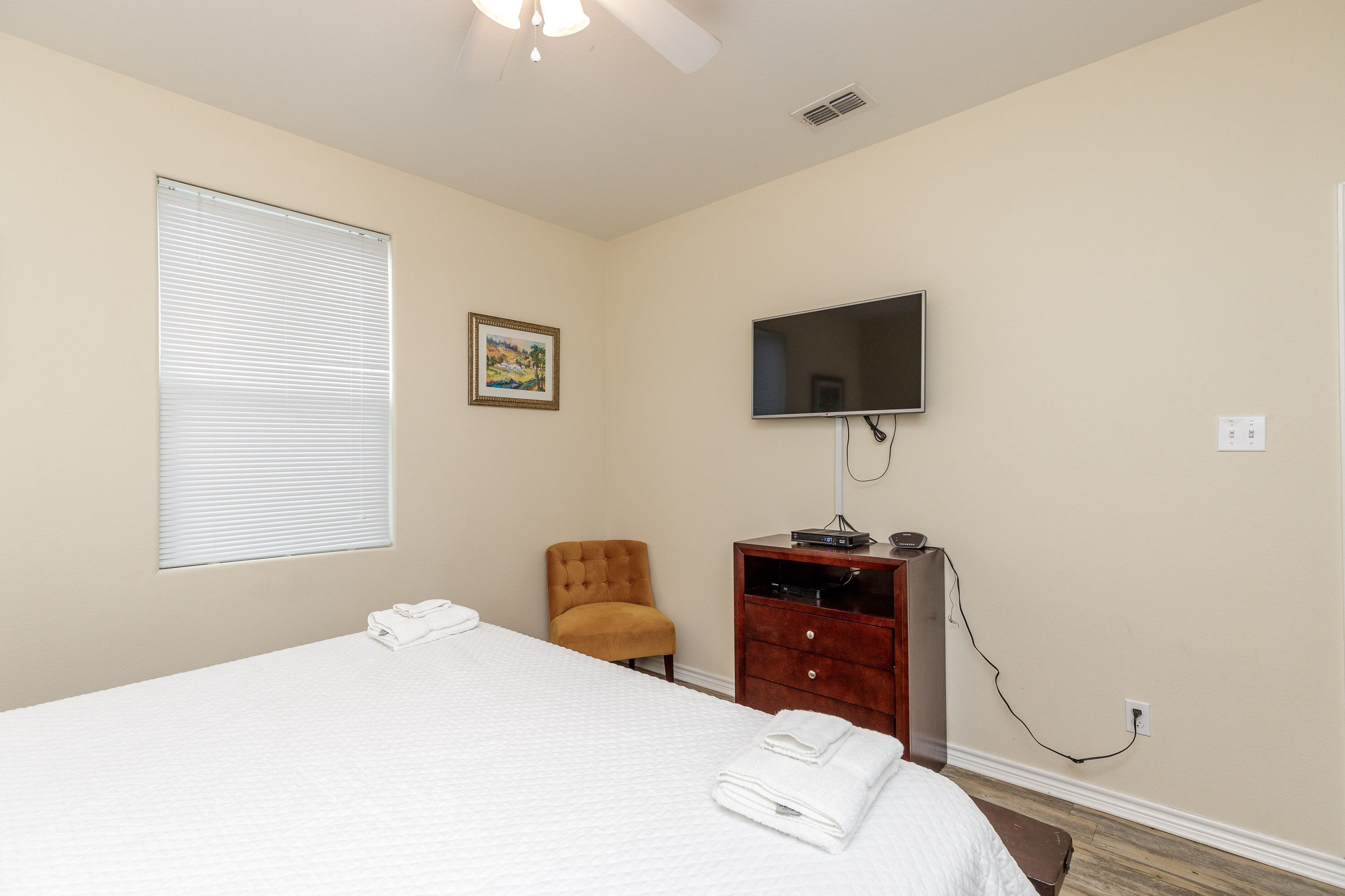 A hotel room with a bed, a TV, a chair, and a desk.