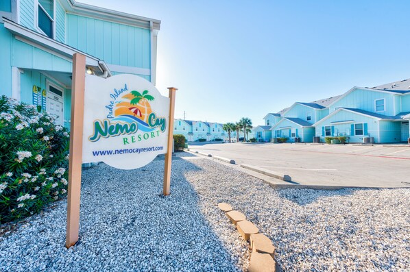 A sign for Nemo Cay Resort with a clear view of the resort's buildings in the background.