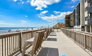 A wooden boardwalk leading to a beach with a clear sky.
