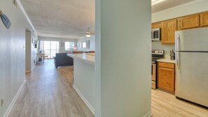 A spacious kitchen with wooden cabinets, a stainless steel refrigerator, and a dining area with a table and chairs. - Seasider 302 - Two-bedroom, Two & 1/2 Bath Oceanfront Condo (Garden City Beach)