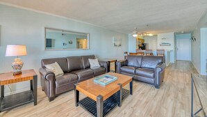A living room with two leather sofas, a wooden coffee table, a lamp, and a mirror on the wall. - Seasider 302 - Two-bedroom, Two & 1/2 Bath Oceanfront Condo (Garden City Beach)