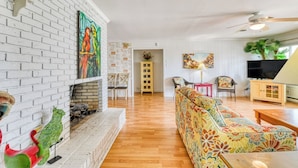A living room with a fireplace, colorful artwork, a sofa, and a television.