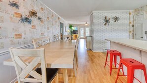 A kitchen with a wooden table, red stools, and a white brick wall.