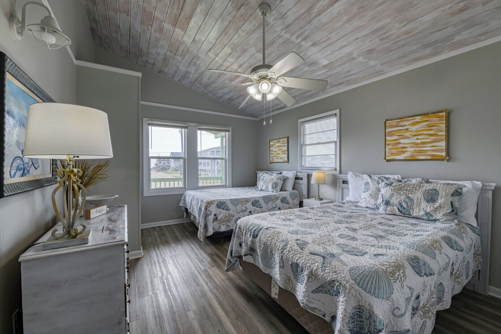 A bedroom with two beds, a ceiling fan, and a view of the outside.