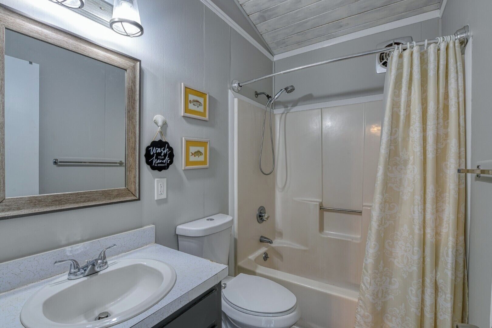 A bathroom with a sink, toilet, shower, and a mirror.