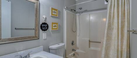 A bathroom with a sink, toilet, shower, and a mirror.
