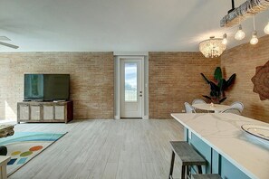 A living room with a TV, wooden cabinet, and a dining area with a table and chairs.