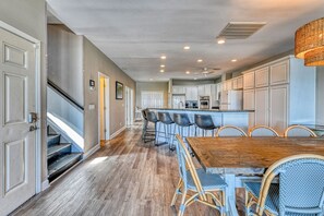 A spacious kitchen with a central island, bar stools, and a dining table with chairs. - T's Treasure's - Eight-bedroom, eight-bath oceanfront duplex w/ pool (Surfside Beach)
