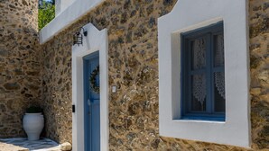 A stone building with a blue door and window, a white wall, and a stone pathway.