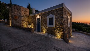 A stone building with a blue door and a small window, illuminated by warm lighting.