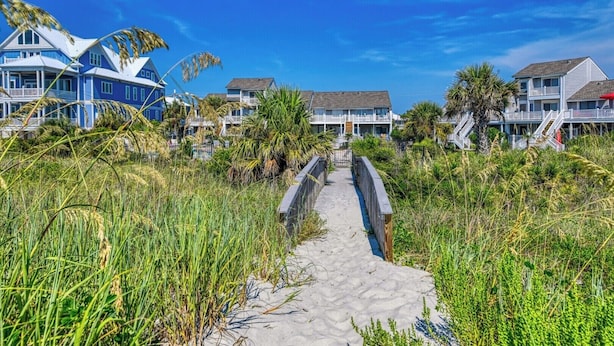 A coastal pathway leading to beachfront properties with a clear sky.