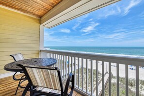 A covered outdoor area with a table and chairs, overlooking a beach.