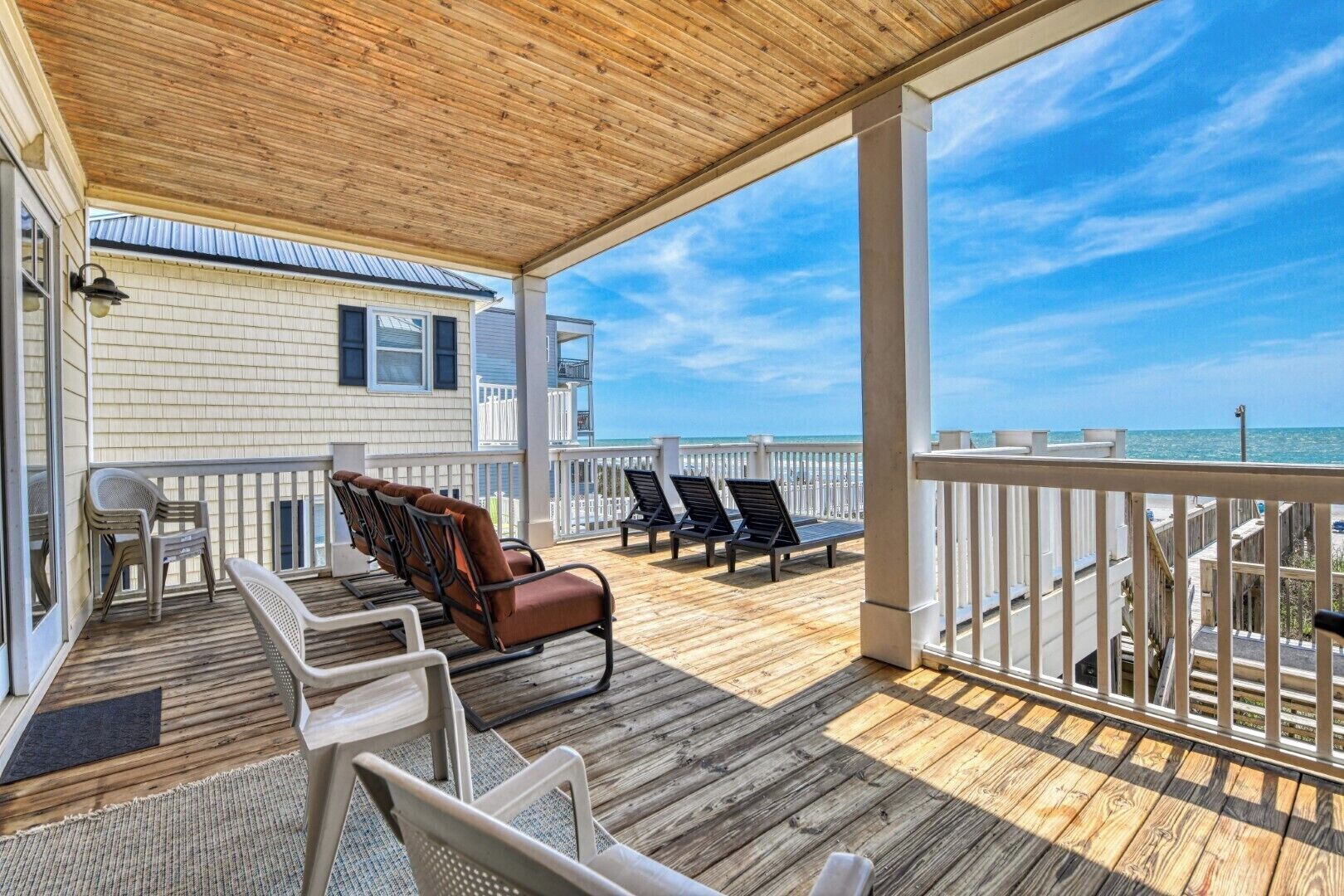 A covered outdoor area with wooden flooring, a wooden ceiling, and a view of the ocean.
