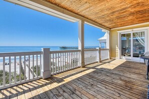A covered deck with a view of the beach and ocean.