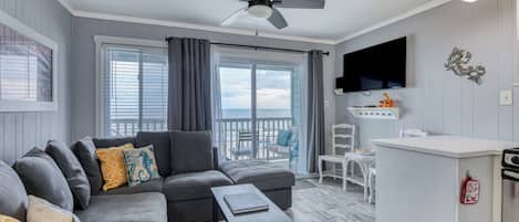 Una sala moderna con un sofá gris, una mesita y un balcón con vistas.