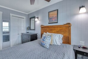 Un dormitorio con cama, cómoda, espejo y lámpara de pared.