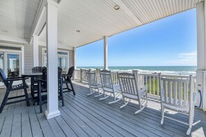 A covered outdoor deck with a view of the ocean, featuring a table and chairs. - Ocean Air - 8 bedroom, 6 1/2 bath Oceanfront Home with Private Pool (Garden City Beach)