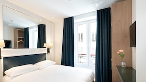 A hotel room with a bed, a mirror, a small table with a vase of flowers, and a view of the outside balcony. - Hotel au coeur des Arts et Metiers (Paris)