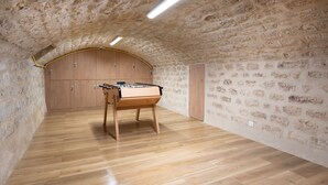 A room with a wooden foosball table, stone walls, and a wooden door. - Hotel au coeur des Arts et Metiers (Paris)