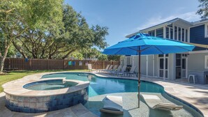 Un patio trasero con piscina, jacuzzis y un área de patio techada.