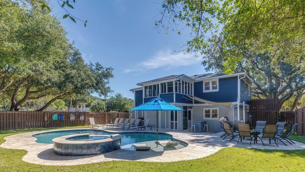 Un patio trasero con piscina, un porche techado y mobiliario exterior.