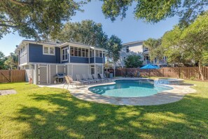 A two-story house with a backyard featuring a swimming pool, a barbecue grill, and outdoor seating.