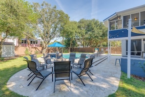 A backyard with a pool, outdoor seating, and a covered patio area.